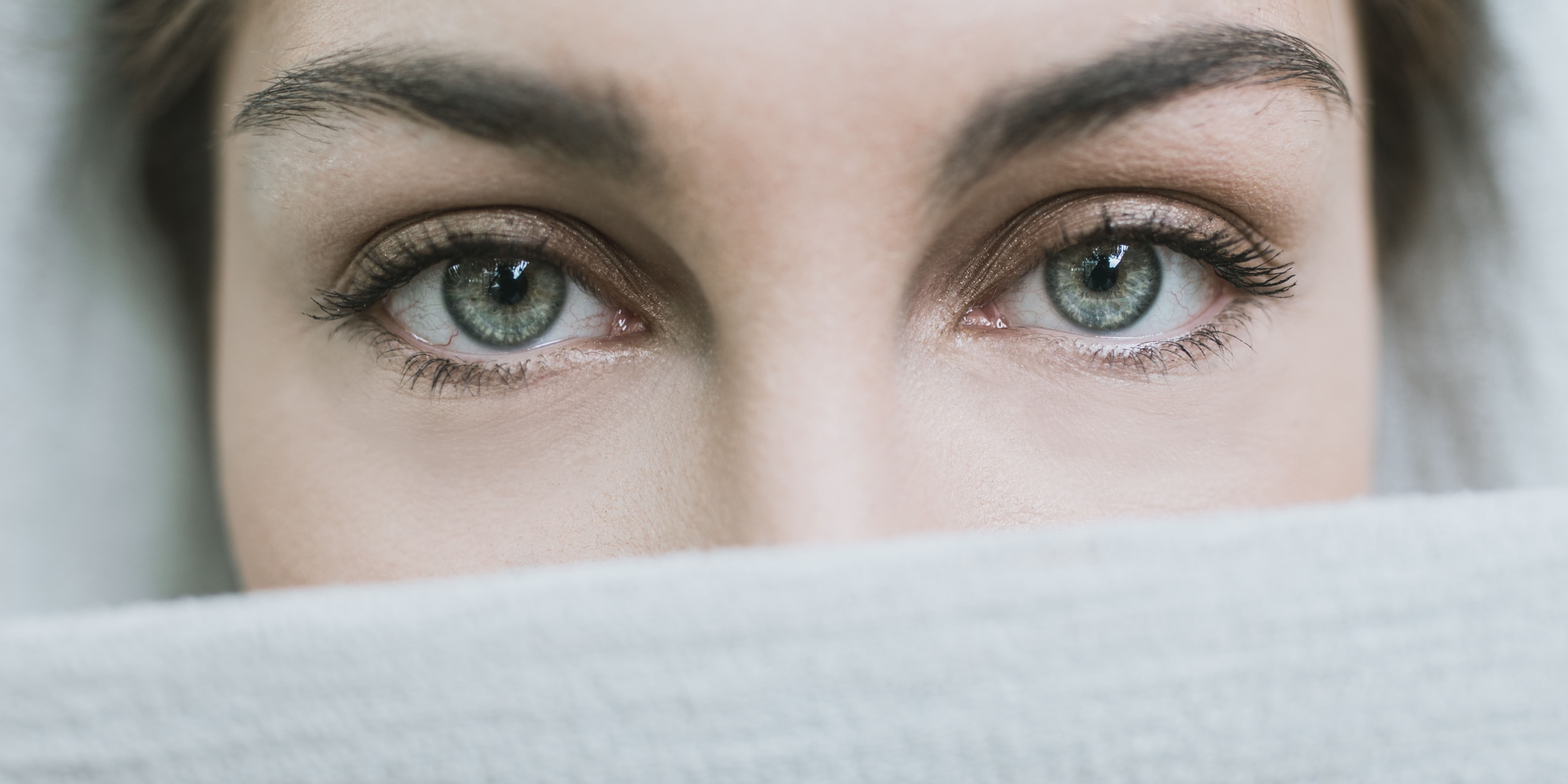 Priestess banner image A woman looks directly ahead with piercing eyes, her head and the lower half of her face covered by a white veil.